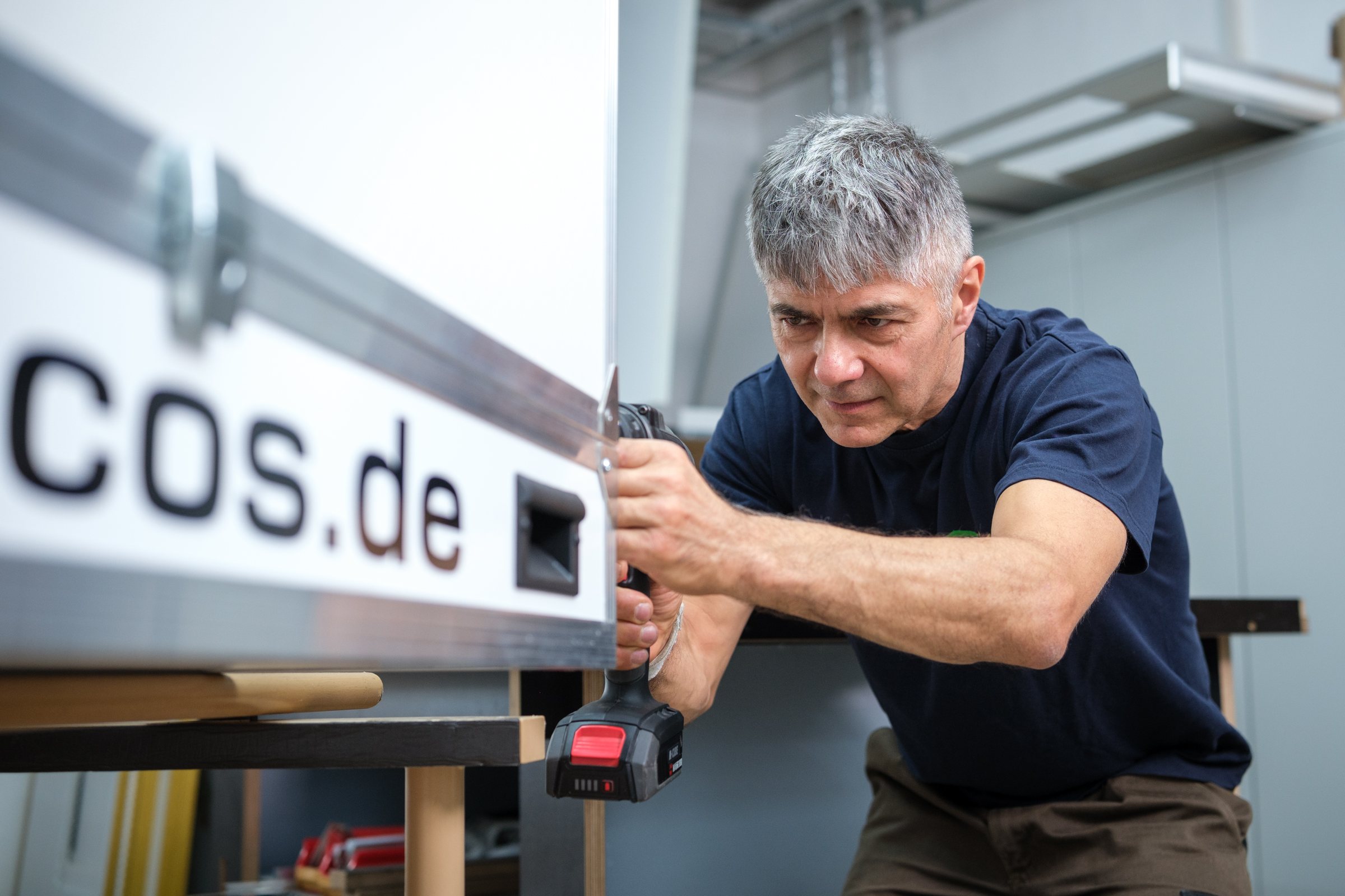 Handwerker montiert ein beleuchtetes Firmenschild in der Werkstatt